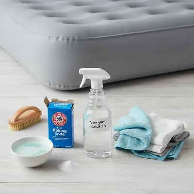 Essential cleaning supplies for an air mattress, including mild soap, white vinegar, baking soda, and soft cloths.